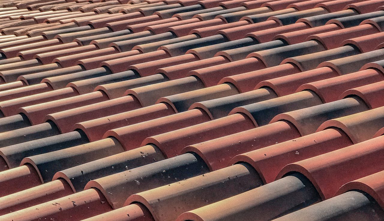 contact-bg A detailed view of overlapping terracotta roof tiles creating a pattern, capturing a classic architectural style.